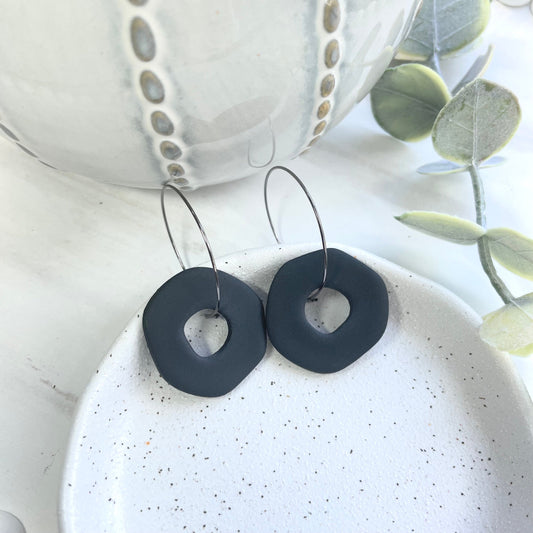 Black abstract polymer clay circle earrings on a black hoop,